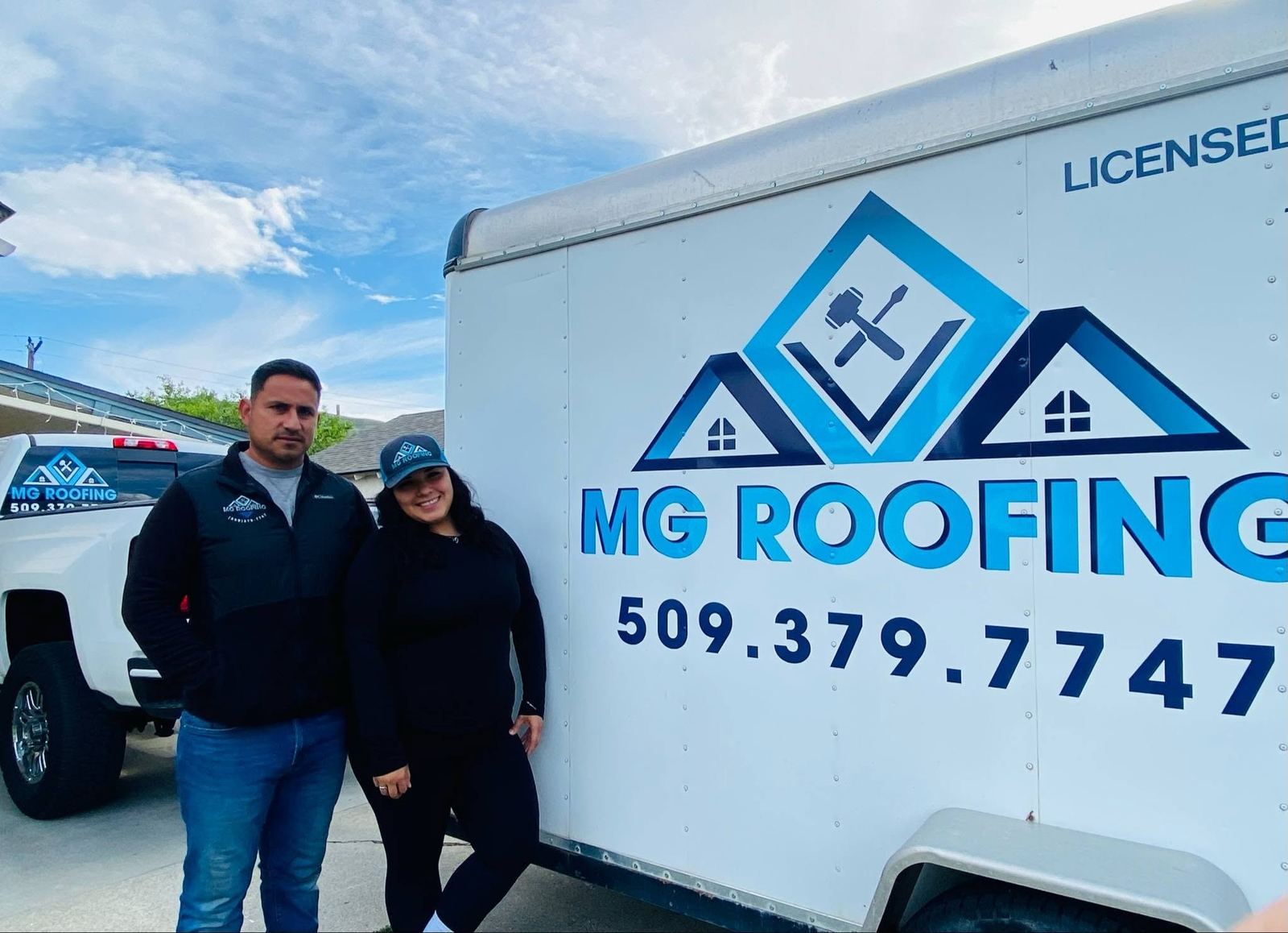 MG Roofing owners standing with their work trailer